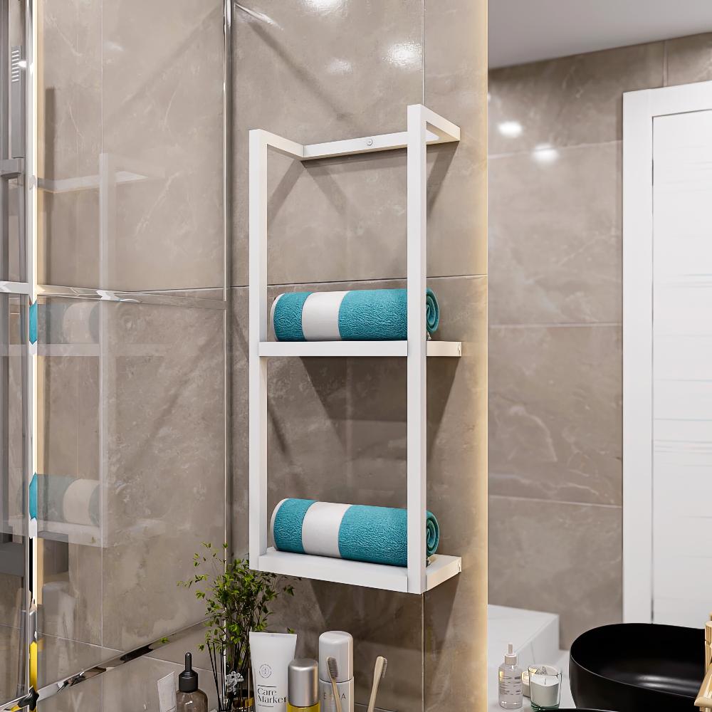 Her bir katında düzenli bir şekilde rulo yapılmış teal havlular bulunan, bej fayanslı bir duvara, çeşitli banyo malzemeleri bulunan bir tezgahın üzerine monte edilmiş iki katlı beyaz metal banyo rafı.