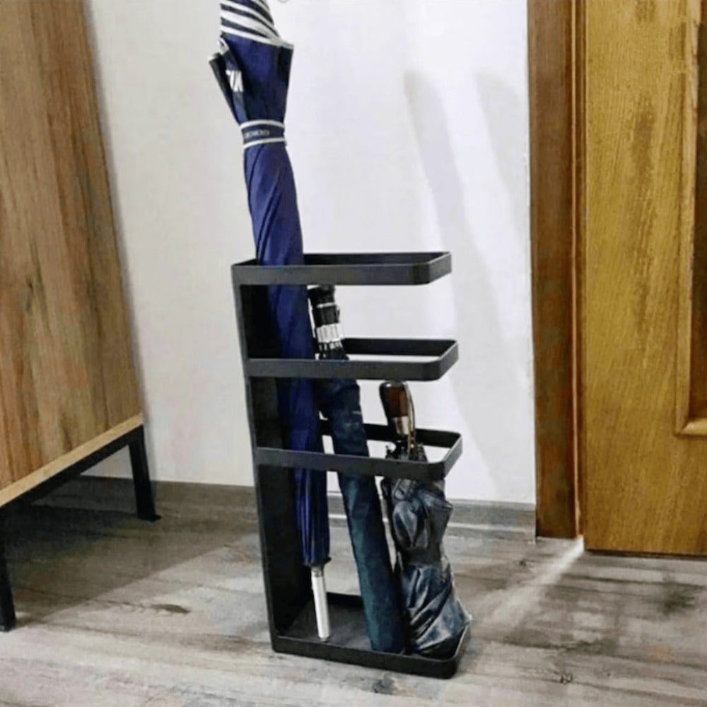 Çok sayıda şemsiyeyi tutan siyah bir şemsiyelik, ahşap ve nötr vurgularla çağdaş bir iç mekanda konumlandırılmış.