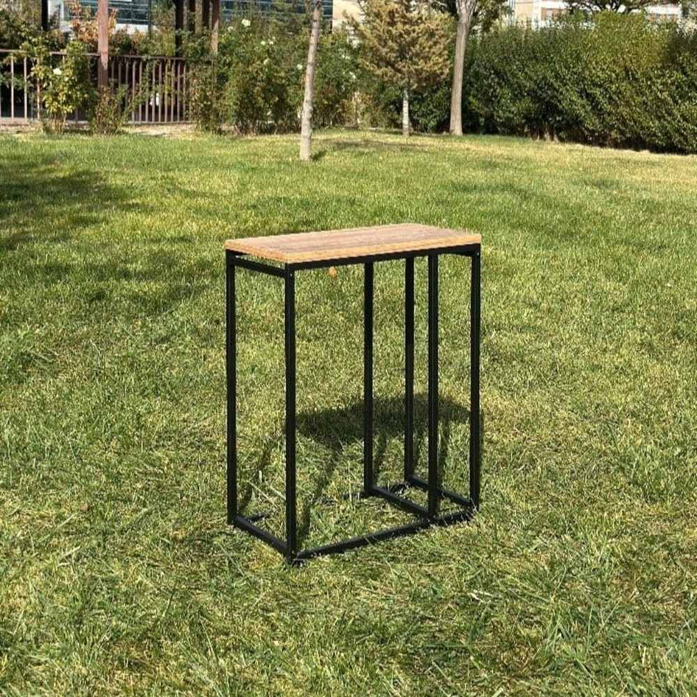 Dış mekanda, çimlerin üzerinde sergilenen, zarif ve modern tasarımını gözler önüne seren, ahşap tablası olan, boş minimalist siyah metal bir odunluk.