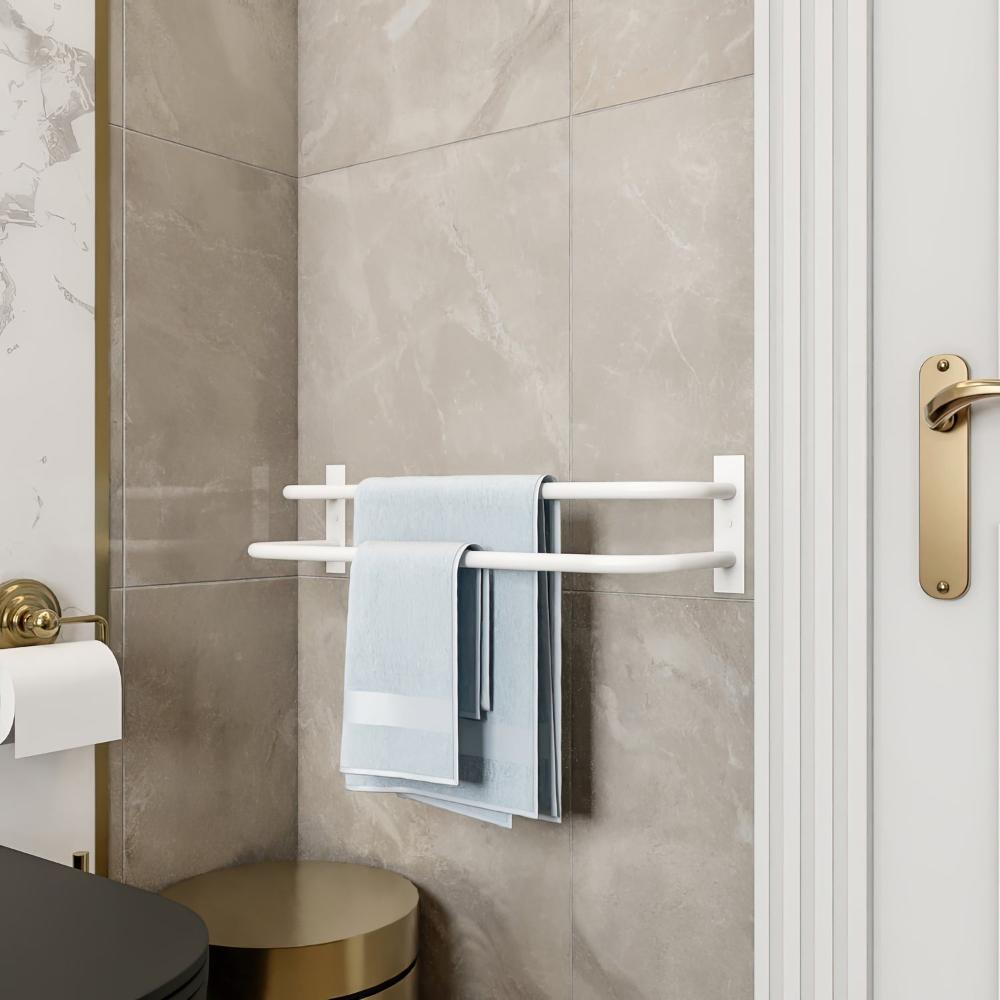 Temiz ve minimalist bir banyo ortamında, duvara monte edilmiş beyaz çift barlı havluluk, düzenli katlanmış mavi havluları tutuyor. Fayansların nötr tonları ve altın rengi kapı kolu, genel tasarıma zarif bir dokunuş katıyor.