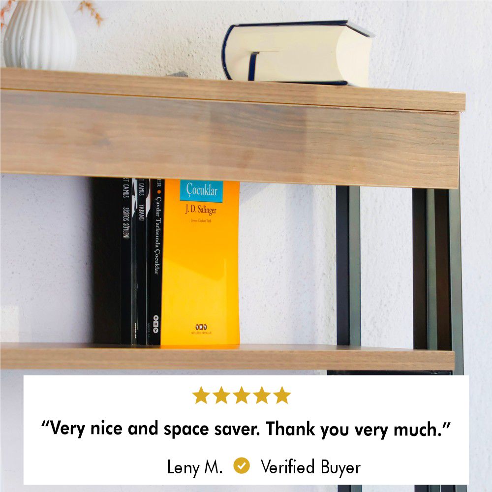 A close-up shot of a wooden shelf supported by black metal brackets, showcasing a few books, including one with a bright yellow cover and a vase placed on the top level against a white wall.