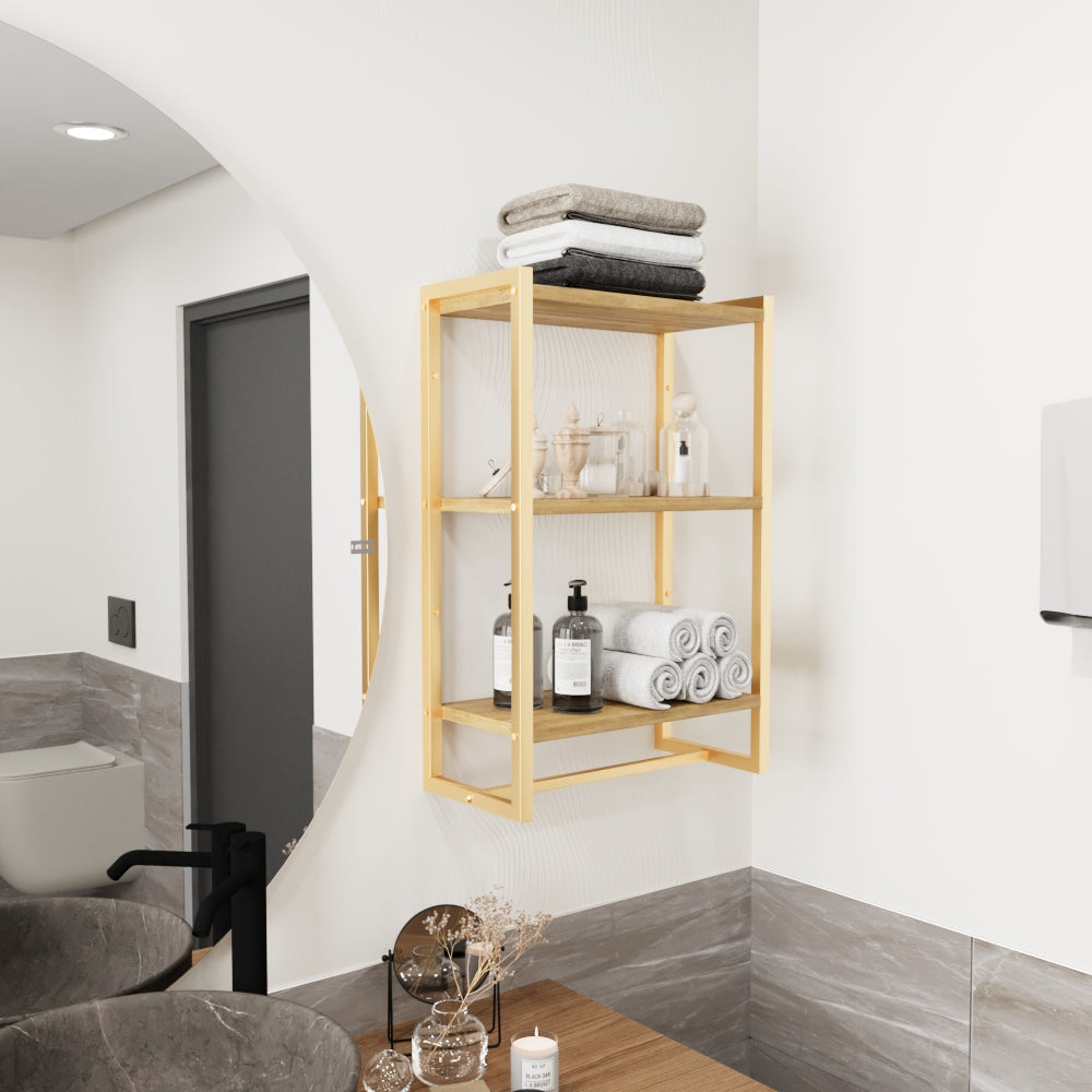 Duvara monte edilmiş, üç ahşap rafa sahip goldmetal bir havluluk. Raflarda katlanmış ve rulo yapılmış havlular, ayrıca dekoratif cam şişeler ve sabunluklar düzenli bir şekilde sergilenmektedir.