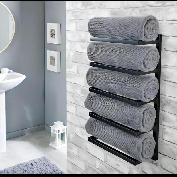 Duvara monte beş katlı siyah havluluk, modern bir banyoda yuvarlak ayna ve minimalist dekorla beyaz tuğla duvara karşı rulo gri havluları tutuyor.