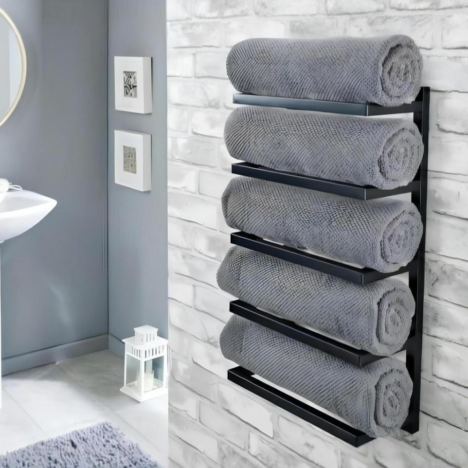 Duvara monte beş katlı siyah havluluk, modern bir banyoda yuvarlak ayna ve minimalist dekorla beyaz tuğla duvara karşı rulo gri havluları tutuyor.