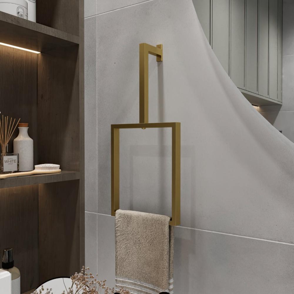 Açık gri bir duvara monte edilmiş minimalist gold renkli dikey bir havlu halkası. Modern dikdörtgen tasarım, bej bir havlu tutarak banyo dekoruna temiz ve şık bir dokunuş katıyor. Şık havlu halkası, çevredeki nötr tonları ve sade tasarım öğelerini mükemmel bir şekilde tamamlayarak mekanın minimalist estetiğini güçlendiriyor.