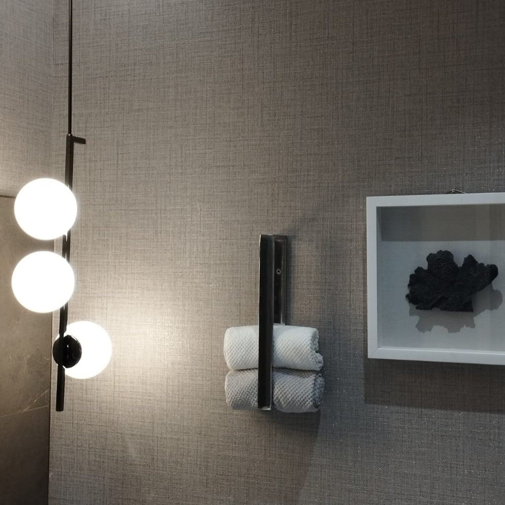 Krom havluluğun yansıtıcı yüzeyini vurgulayan, modern aydınlatmalı ve krom havluluklu bir banyo düzenlemesi.