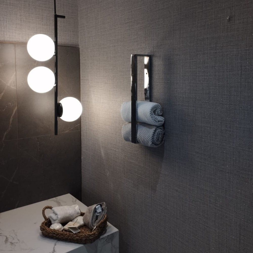 Temiz ve minimalist tasarımı vurgulayan, düzenli bir şekilde yerleştirilmiş rulo havluları olan krom bir havluluğun yandan açılı görünümü.