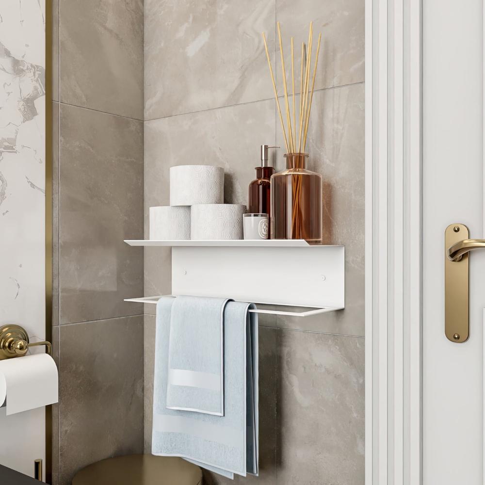 Beyaz bir havluluk ve raf, bambu çubuklu difüzörler ve banyo malzemeleriyle süslenmiş olup, lüks bir banyo estetiğini tamamlıyor.