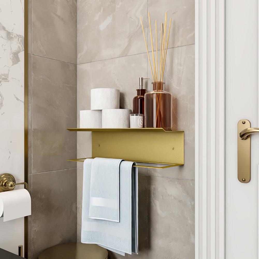 Altın renkli bir havluluk ve raf, banyo malzemeleri ve bambu çubuklu difüzörlerle dekore edilerek banyo ortamına zarif bir dokunuş katıyor.