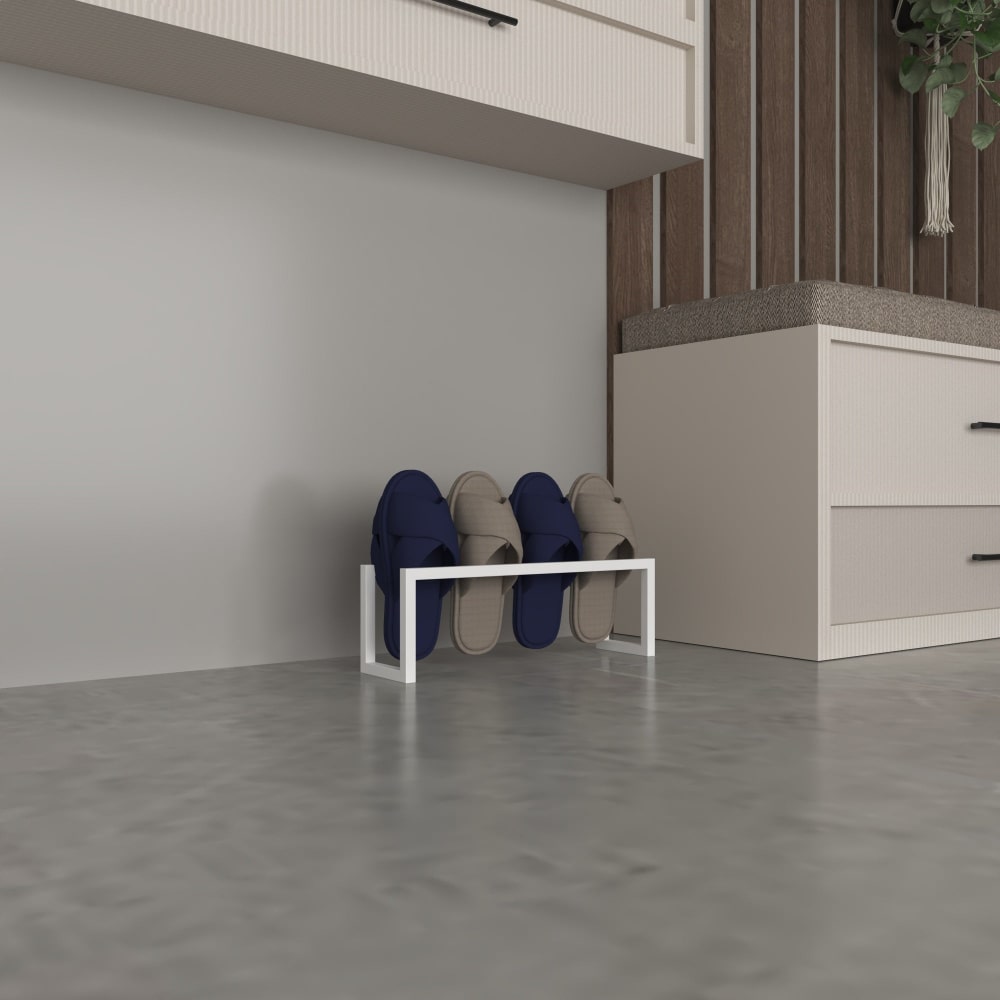 Duvara yaslanmış, minimalist bir alanda mavi ve gri terlikleri tutan beyaz metal bir terlik rafı.