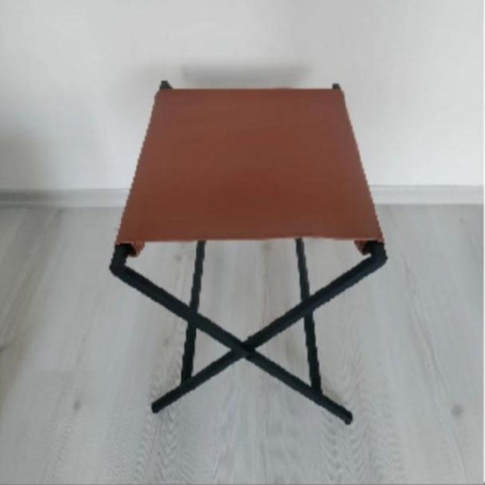 Minimalist katlanabilir metal bavul rafı, hakiki deri yüzeyiyle düz beyaz bir arka plana karşı çekilmiştir.