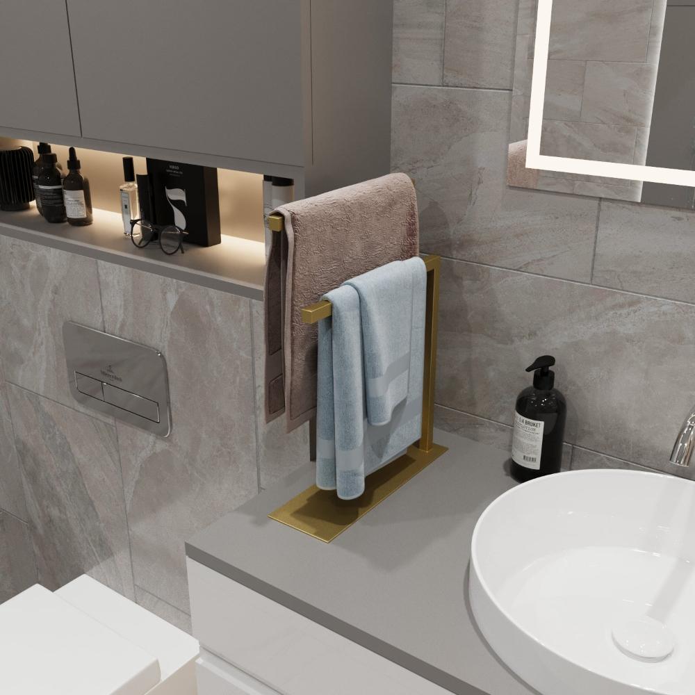 Banyo tezgahına yerleştirilmiş altın renkli bir tezgah üstü havluluk, havluları düzenli tutarken dekora lüks bir dokunuş katıyor.