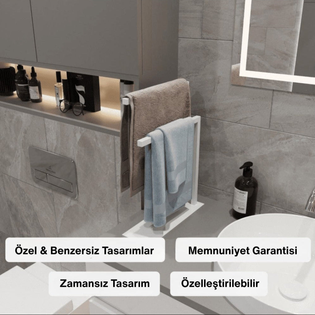 Modern bir banyoda lavabonun yanında konumlandırılmış beyaz metal tezgâh üstü havluluk üzerinde kahverengi ve mavi havlular yer almaktadır. Ürün, kişisel dekor ve iç-dış mekân kullanımı için uygun olup zamansız bir tasarıma sahiptir.