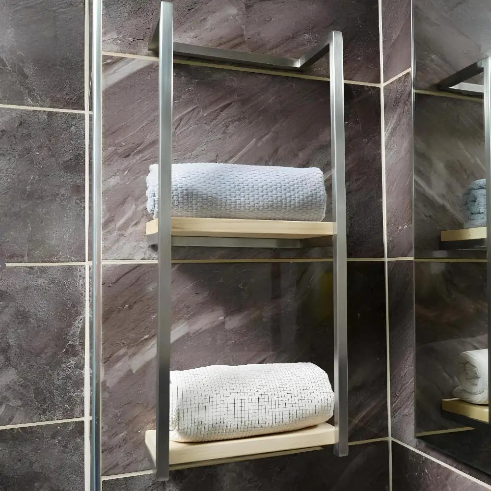 Modern bir banyo ortamında saten nikel kaplamalı duvara monte bir havluluk görüntüsü. Havluluk, her biri düzenli bir şekilde rulo yapılmış beyaz bir havluyu tutan iki ahşap rafa sahiptir.