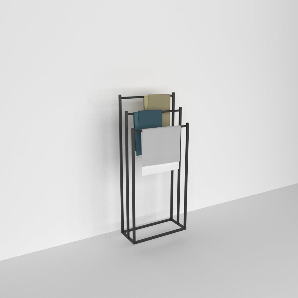 Düz beyaz bir duvara ve açık gri bir zemine karşı konumlandırılmış, modern ve minimalist tasarıma sahip, üzerinde bej, teal ve açık gri renklerde havluların asılı olduğu şık siyah metal ayaklı bir havluluk.