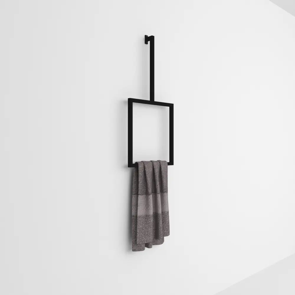 Düz beyaz bir arka plana karşı minimalist bir tasarımda gri bir havluyu tutan duvara monte siyah dikey havluluk.