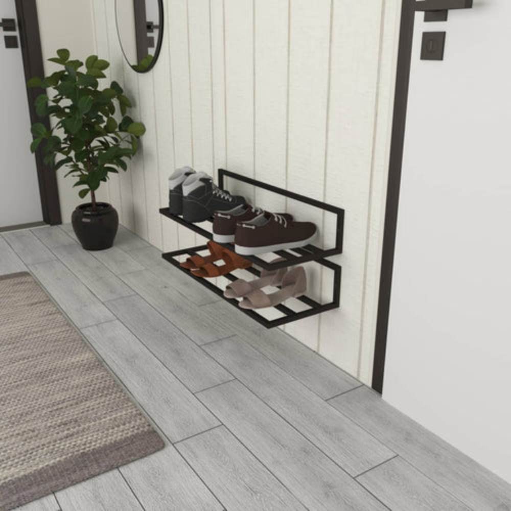 Botlar, spor ayakkabılar ve topuklular dahil çeşitli ayakkabıları düzenli bir şekilde tutan, saksı bitkisi ve bej panelli bir duvarın bulunduğu modern bir giriş alanına yerleştirilmiş, iki katlı siyah duvara monte bir ayakkabılığın yandan görünümü.