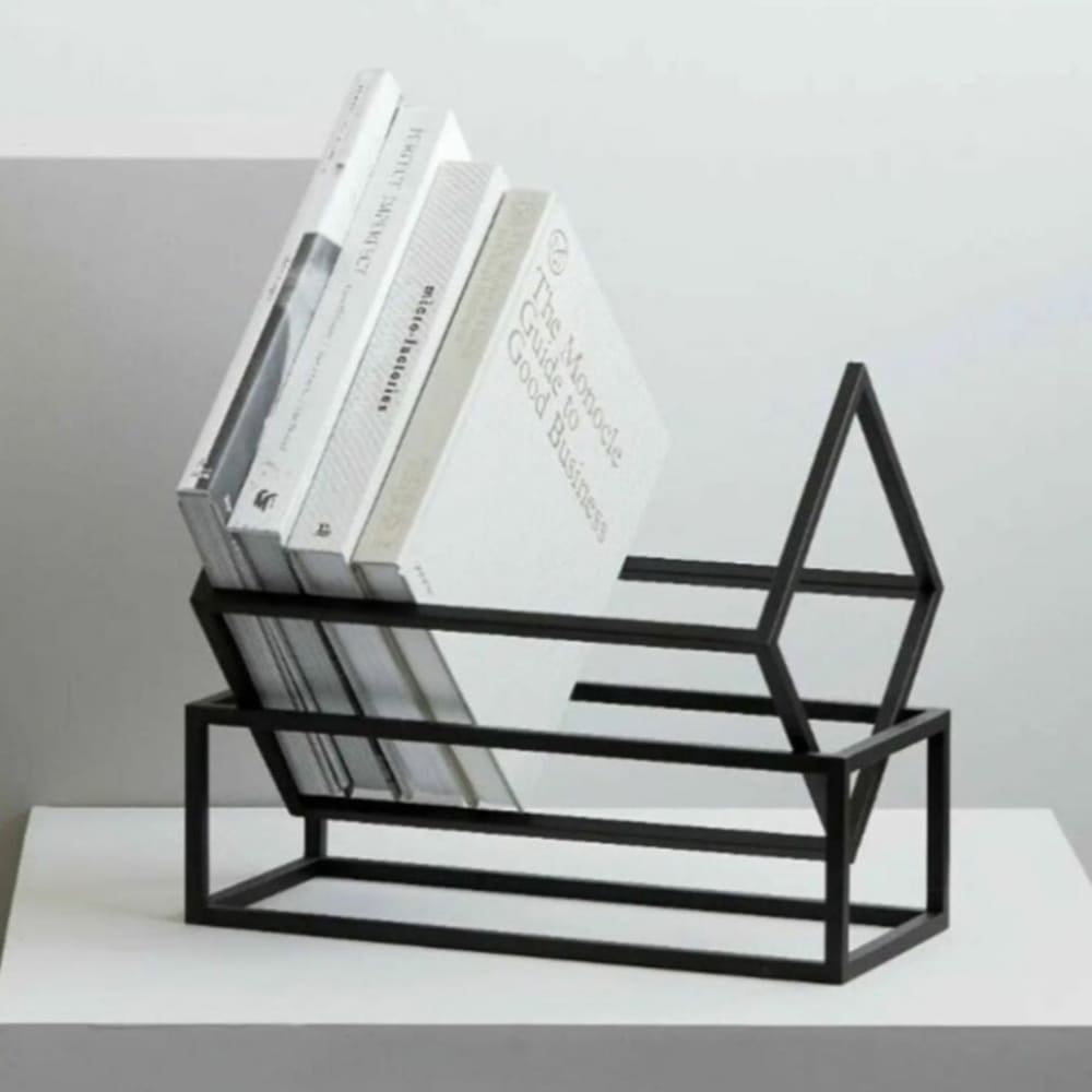 Beyaz bir kaide üzerinde, modern minimalist bir tarzda tek renkli kitap seçkisini tutan siyah geometrik bir kitap rafı.