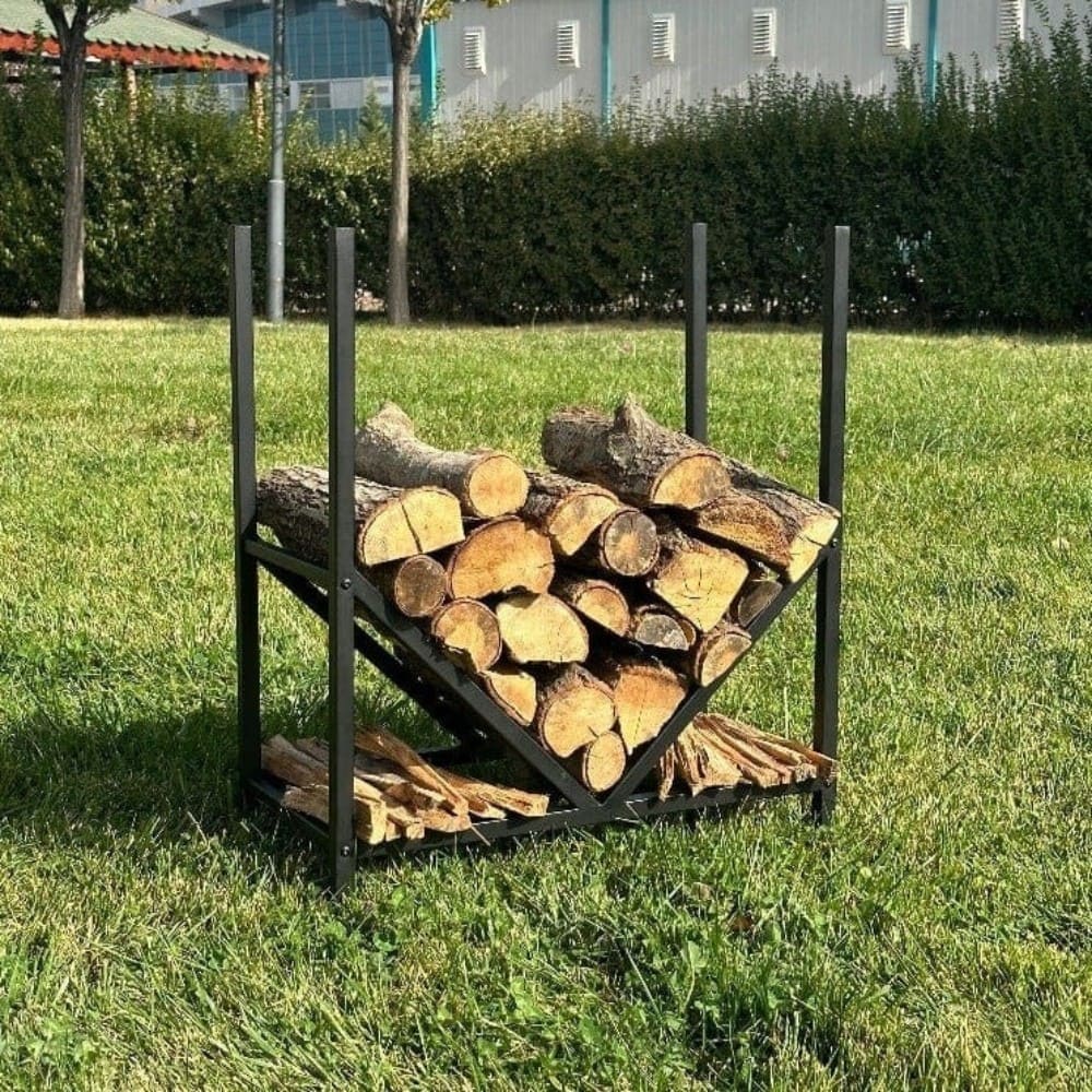 Dış mekanda, çimenlik bir bahçe alanına yerleştirilmiş, içinde odun ve tutuşturucuların düzenlendiği, geometrik V şeklinde bir yapıya sahip modern siyah metal bir odunluk.