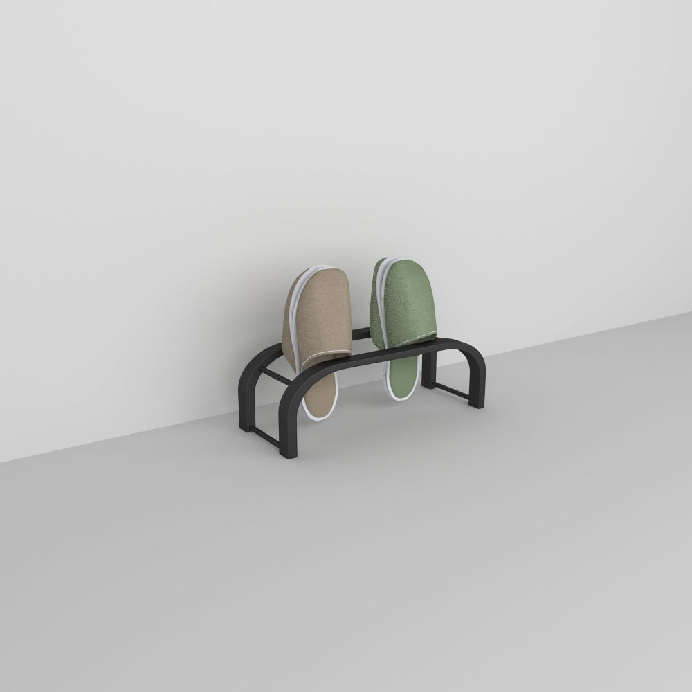 Temiz, minimalist bir ortamda beyaz bir duvara karşı sergilenen, bej ve yeşil terlikleri tutan siyah bir terlik depolama rafı.
