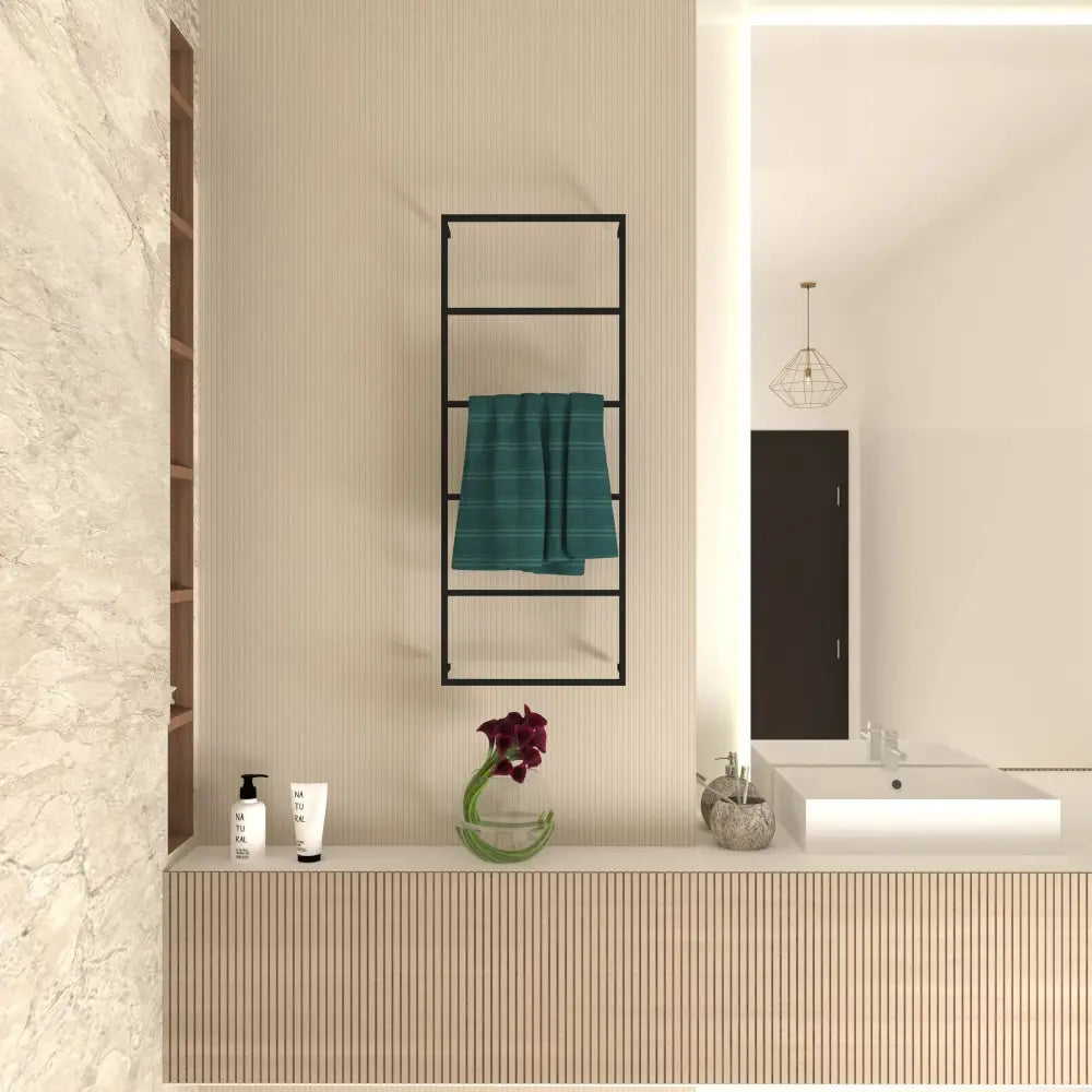 Duvara monte edilmiş 6 katlı, modern siyah metal çerçeveli havluluk, katlanmış camgöbeği rengi bir havluyu tutuyor. Açık bej duvarlar, ahşap vurgular ve çiçek vazosu ile cilt bakım ürünleri içeren dekoratif bir tezgah ile çağdaş bir banyoda yer alıyor.