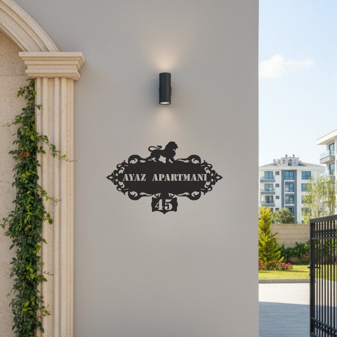 Modern bina girişinde duvara monte edilmiş, aslan figürlü dekoratif metal apartman giriş tabelası