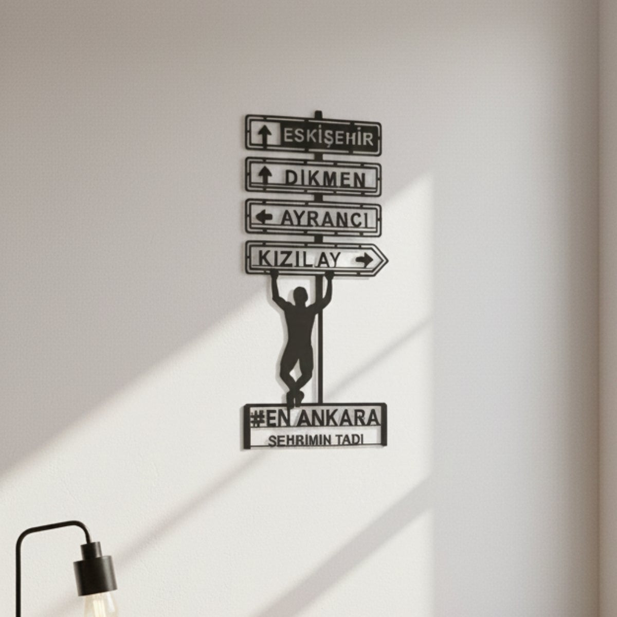Eskişehir, Dikmen, Ayrancı ve Kızılay gibi semt isimlerini içeren, üzerinde direğe tutunan insan figürü bulunan dekoratif siyah metal Ankara tabelası.