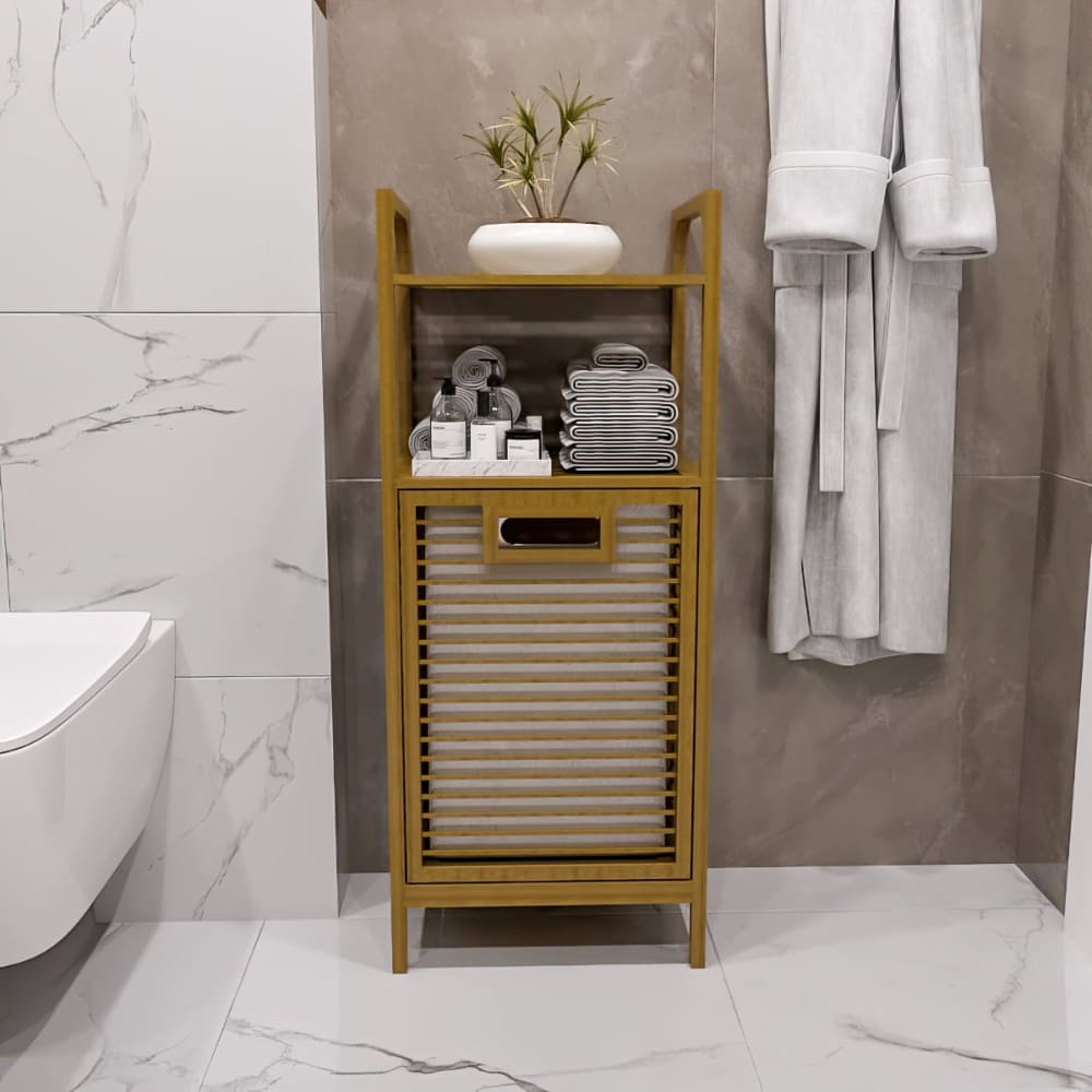 Eğimli çamaşır sepeti, düzenli havlularla dolu açık raflar ve üstünde yeşillik bulunan minimalist bir vazo içeren bambu bir banyo dolabının ön görünümü.