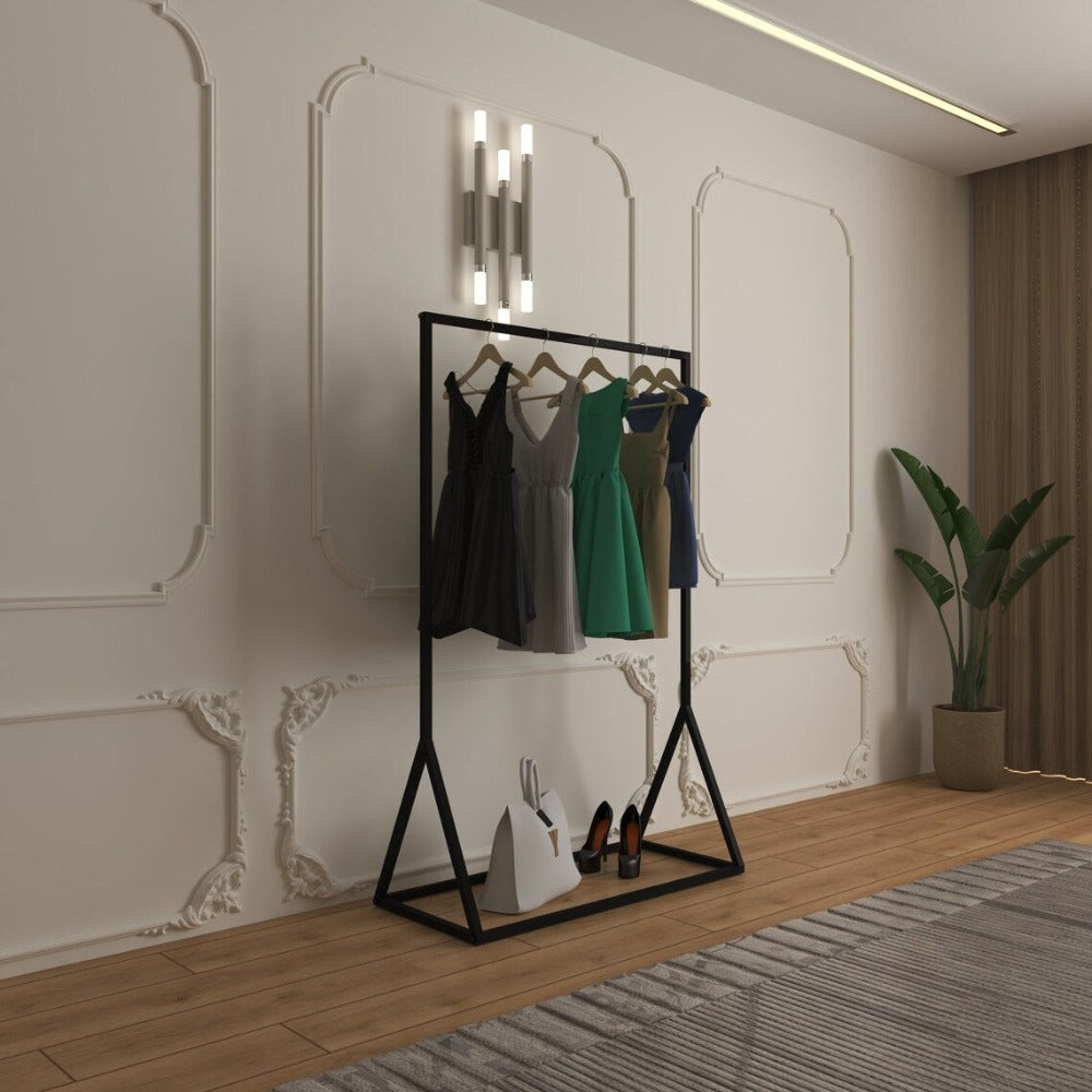 A freestanding clothes rail with a black metal frame, holding several dresses on wooden hangers, with shoes and a bag neatly placed on the bottom shelf in a modern room.