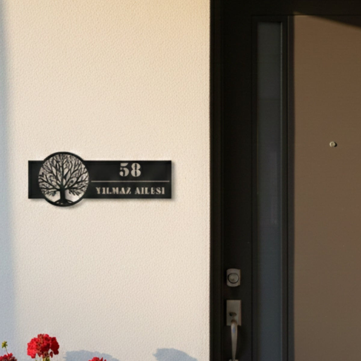 Daire çerçeve içinde detaylı hayat ağacı silüeti ve kişiye özel isim alanı bulunan siyah metal dış mekan tabelası.