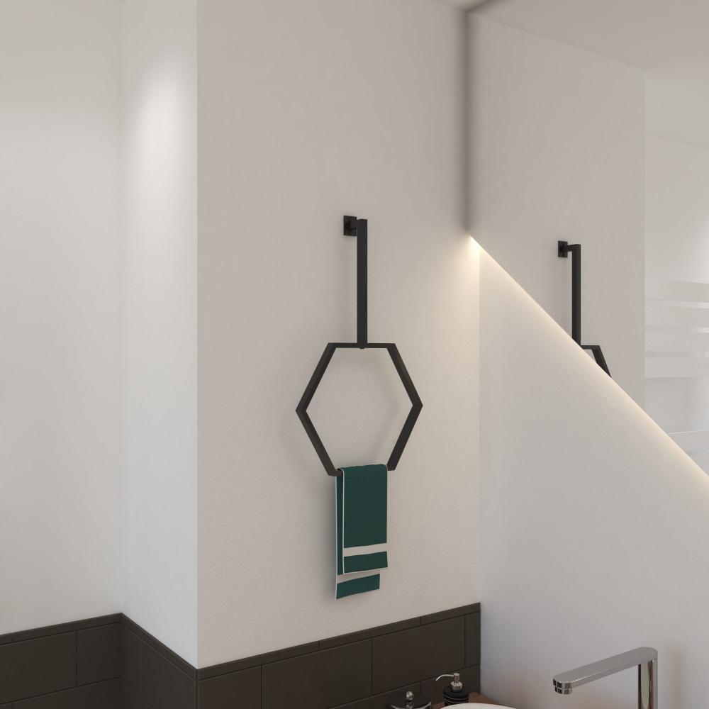 Beyaz bir banyo duvarına monte edilmiş, düzenli bir şekilde asılı yeşil bir havlunun bulunduğu, minimalist tasarımı sergileyen, mat siyah bitişli modern altıgen bir havlu halkası.
