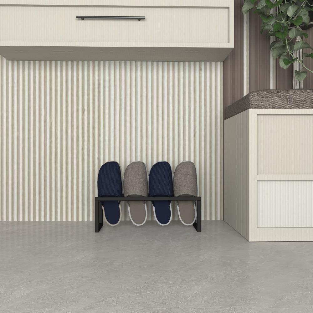Modern metal terlik rafı, dört yuvasında mavi ve gri terlikleri barındırıyor ve minimalist bir koridorda bir dolabın altına yerleştirilmiş.
