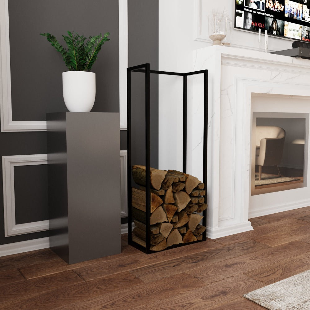 Ahşap zeminli bir oturma odasında, şık bir şöminenin önünde, modern bir kaide üzerinde duran beyaz bir saksılığın yanında yer alan minimalist siyah metal bir odunluk.
