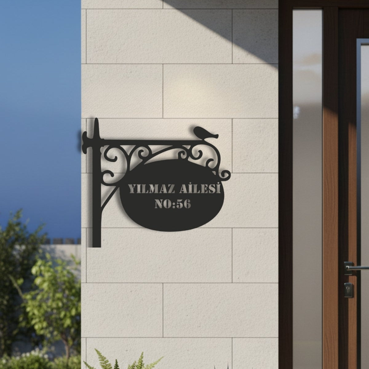 Kıvrımlı ferforje askı detayları ve zarif kuş silüeti ile zenginleştirilmiş, modern lazer kesim işçiliğine sahip siyah metal adres tabelası.