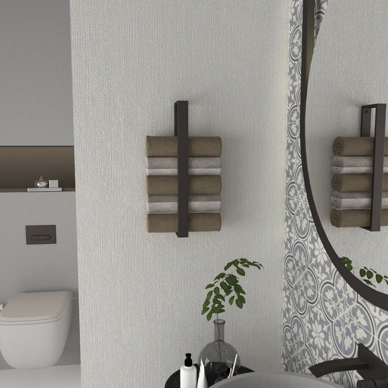 Dokulu bir banyo duvarına monte edilmiş, bej ve gri tonlarında rulo havluları tutan minimalist siyah dikey bir havluluk. Yuvarlak bir ayna ve dekoratif bitkiler modern tasarımı tamamlamaktadır.