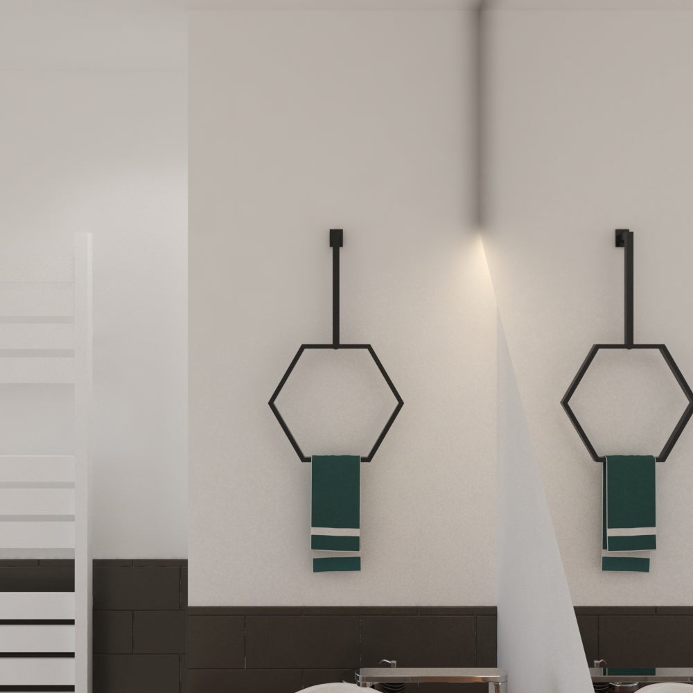Minimalist bir banyo duvarına yan yana monte edilmiş, her biri yeşil havluları tutan, dengeli ve modern bir estetik yaratan bir çift siyah altıgen havlu halkası.
