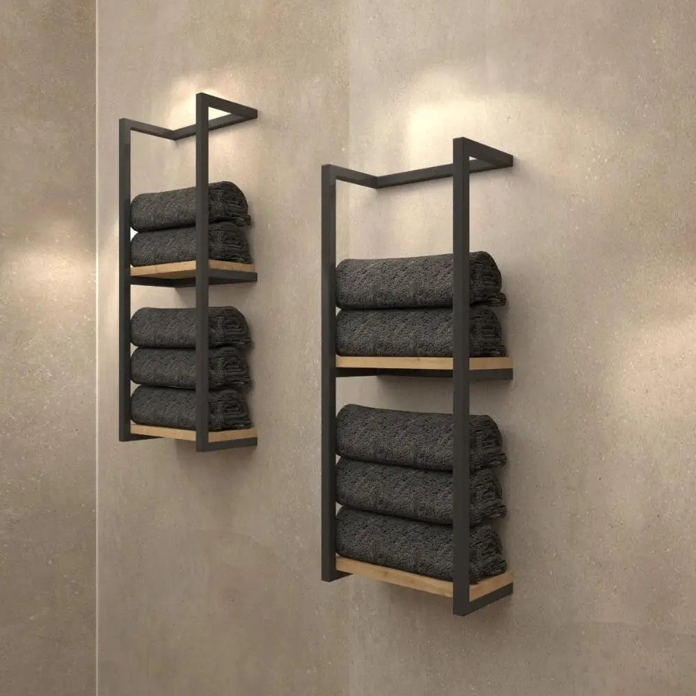 Bej bir duvara karşı, koyu gri havluları düzenli bir şekilde tutan, açık ahşap tabana sahip minimalist siyah metal duvara monte raflar.