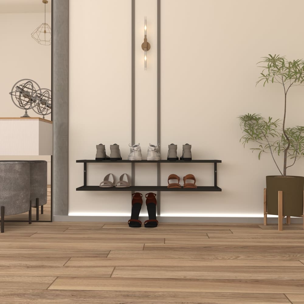 Açık bej bir duvara monte edilmiş, çeşitli ayakkabı çiftlerini sergileyen modern iki katlı siyah metal bir ayakkabılık. Duvarda minimalist dikey aydınlatma bulunmakta ve zemin sıcak ahşap bir tasarıma sahiptir. Küçük saksı bir bitki, sağdaki dekora doğal bir dokunuş katmakta ve arka planda şık bir yaşam alanının bir kısmı görünmektedir.