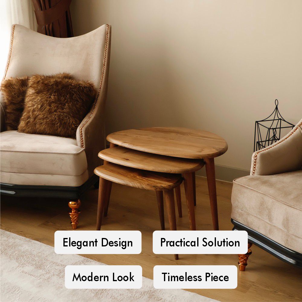 Three wooden nesting tables arranged beside a beige armchair and decorative pillows in a cozy living room setting.